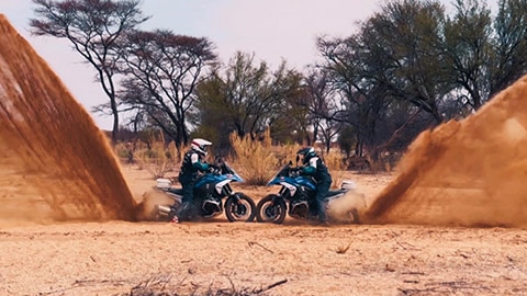 Two riders on the International women’s team kicking up an impressive amount of sand with their rear wheels.